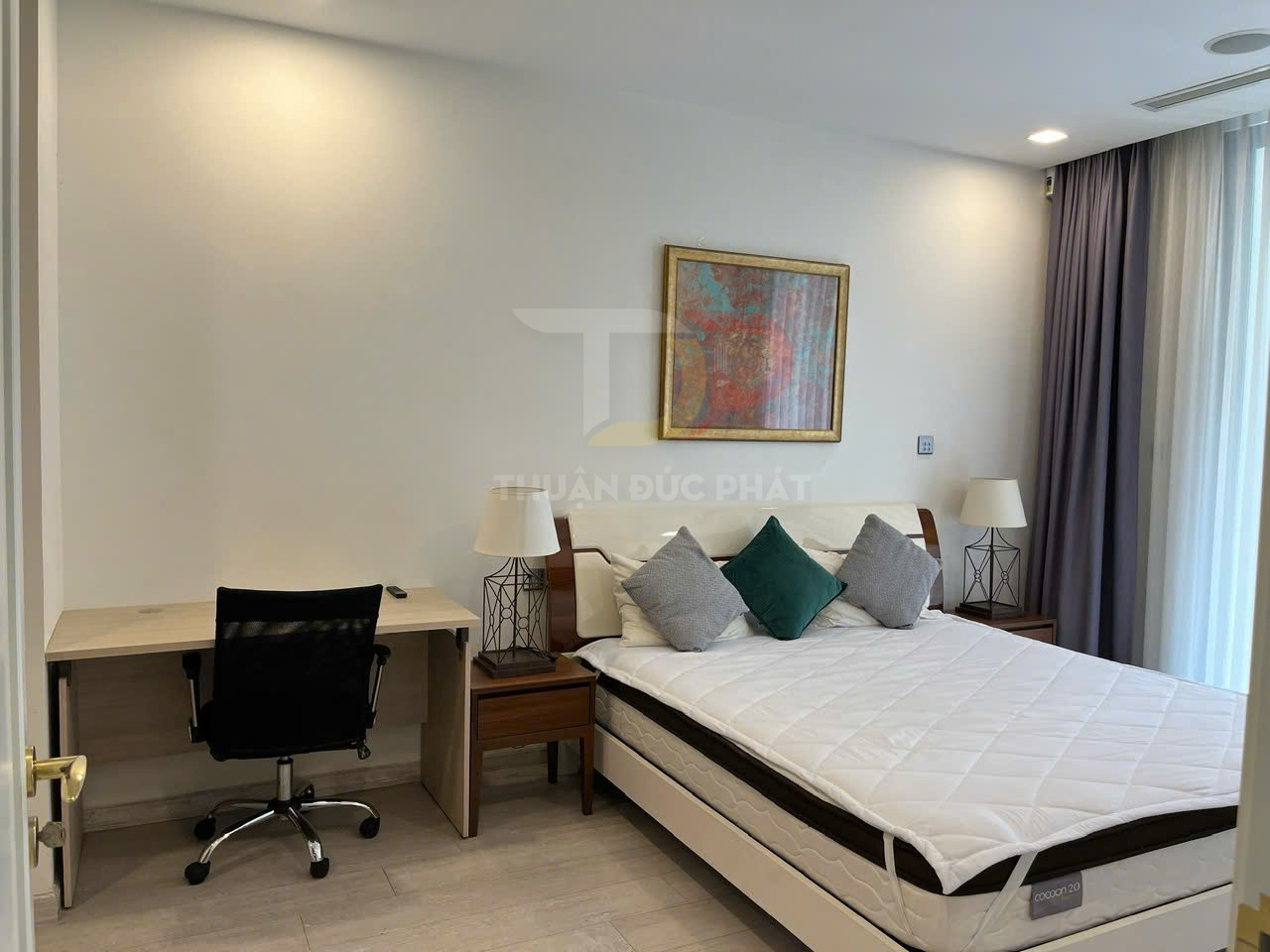 Phòng ngủ hiện đại với giường nệm Cocoon 2.0, bàn làm việc và ghế xoay cạnh cửa sổ lớn có rèm.