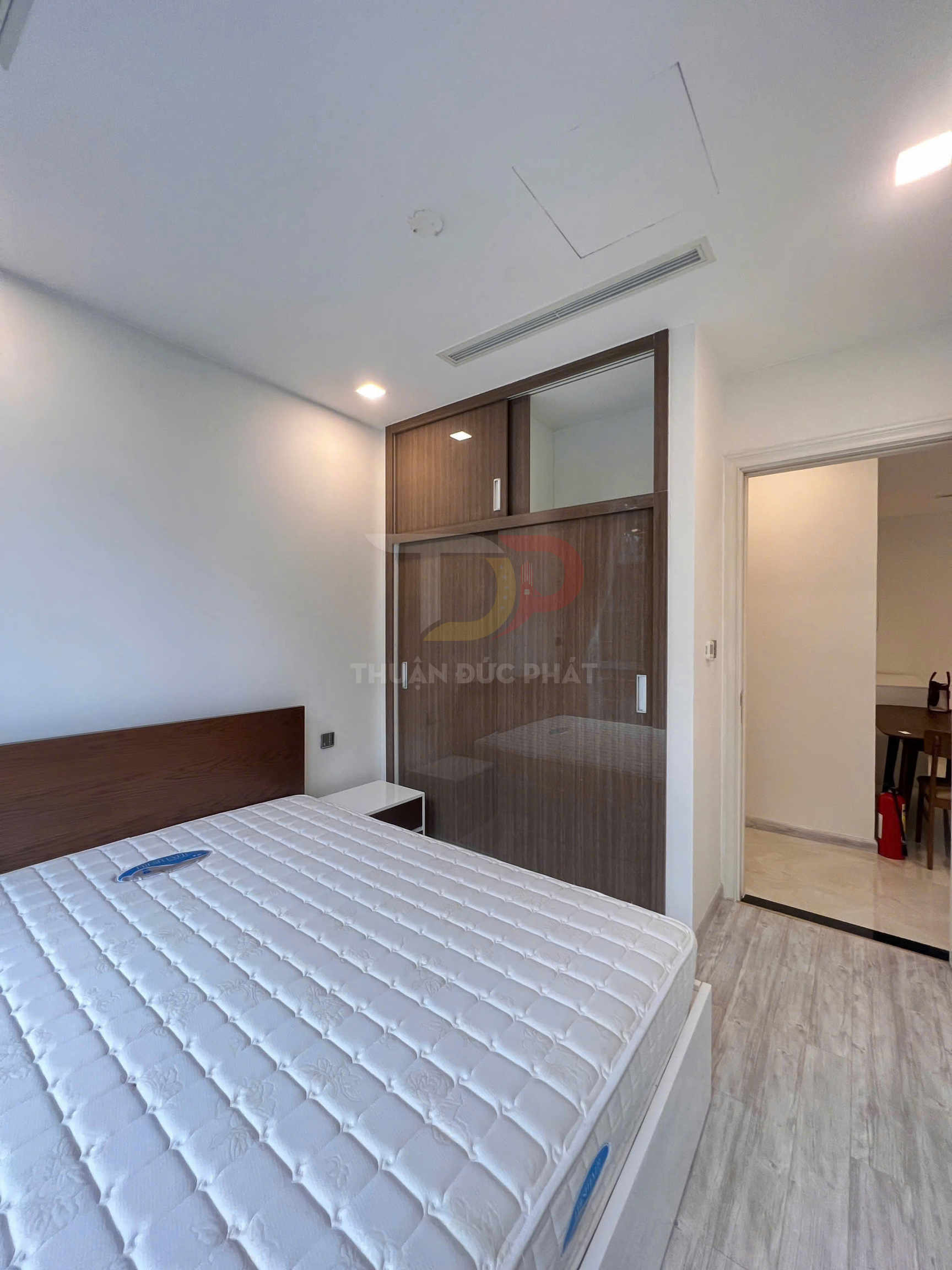 Nệm trắng trên giường gỗ trong phòng ngủ hiện đại với tủ quần áo cửa lùa gỗ kính