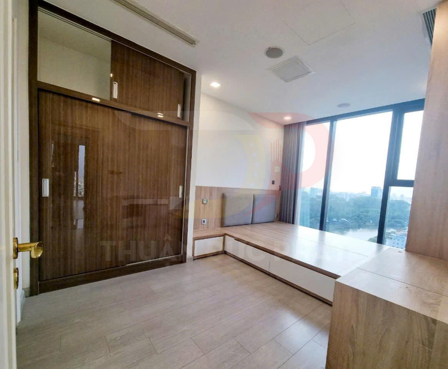 Phòng ngủ chung cư nội thất gỗ hiện đại với giường bệt, tủ âm tường và cửa sổ lớn view thành phố
