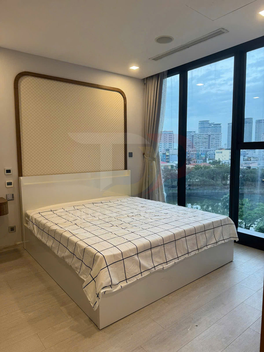 Giường ngủ gỗ màu trắng hiện đại với ga kẻ caro trong phòng ngủ có cửa kính lớn nhìn ra thành phố