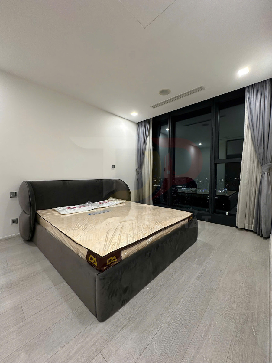 Giường ngủ bọc nỉ màu xám hiện đại với nệm mới trong phòng ngủ có cửa kính lớn nhìn ra ban đêm