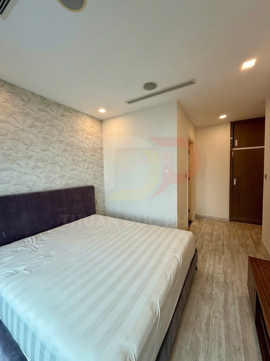 Phòng ngủ hiện đại với giường đôi bọc nệm lớn, sàn gỗ và tường trang trí màu sáng