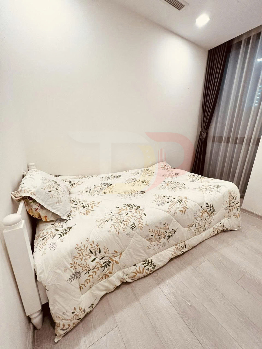Giường đơn với chăn ga gối họa tiết hoa lá trong phòng ngủ tối giản có rèm cửa màu tối
