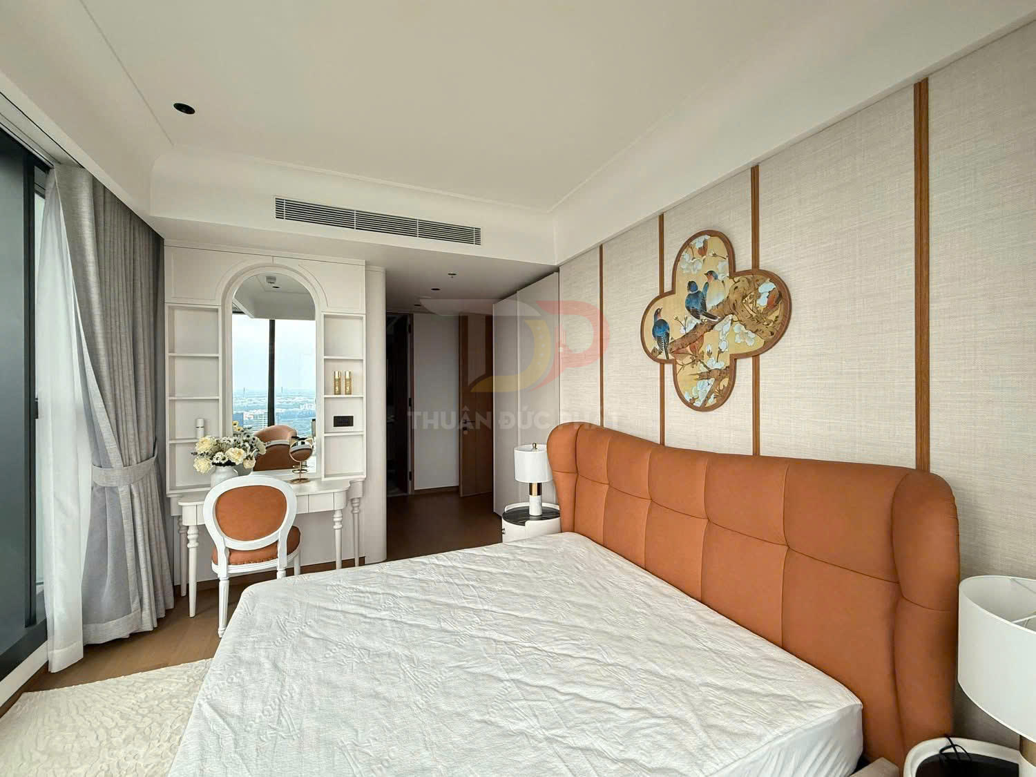 Phòng ngủ hiện đại với giường bọc da cam, bàn trang điểm trắng và cửa sổ lớn tràn ngập ánh sáng