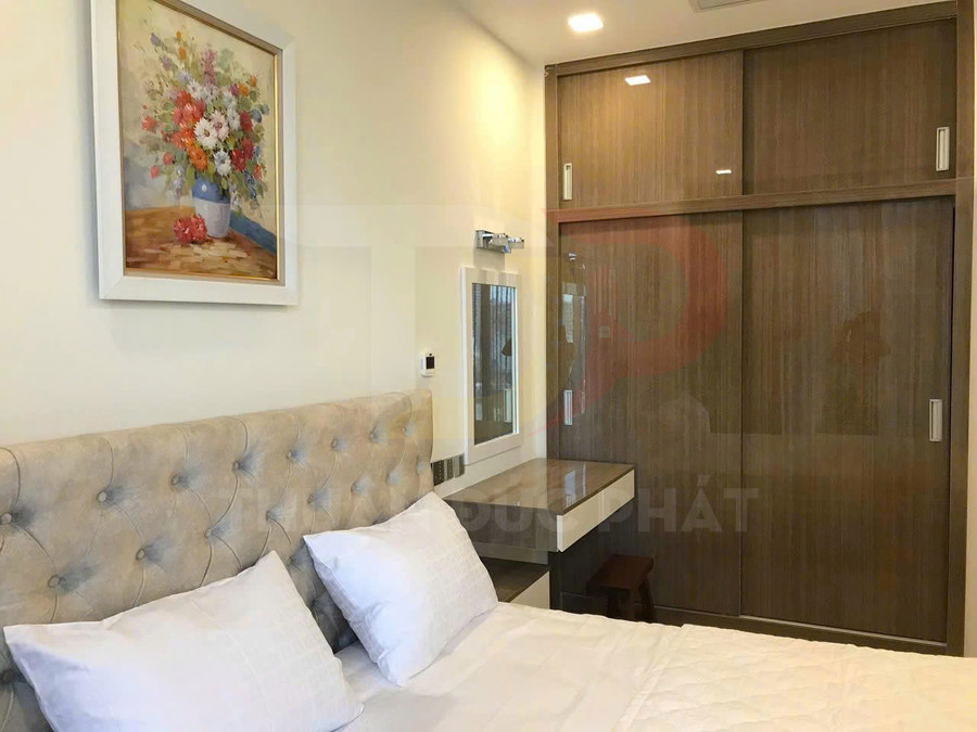 Phòng ngủ với giường bọc nệm đầu giường, tủ quần áo gỗ cửa lùa và bàn trang điểm nhỏ gọn