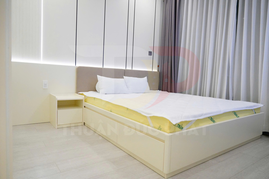 Giường ngủ hiện đại màu trắng với nệm và tấm bảo vệ nệm trong phòng ngủ sáng sủa