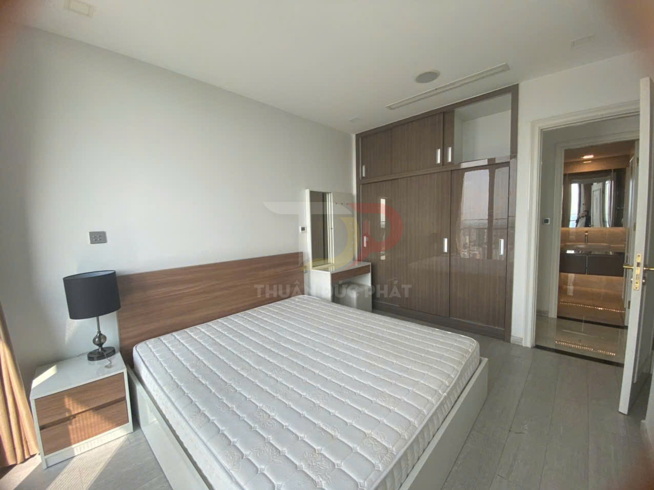 Phòng ngủ hiện đại với giường nệm trắng, tủ quần áo gỗ lớn và bàn trang điểm cạnh phòng tắm