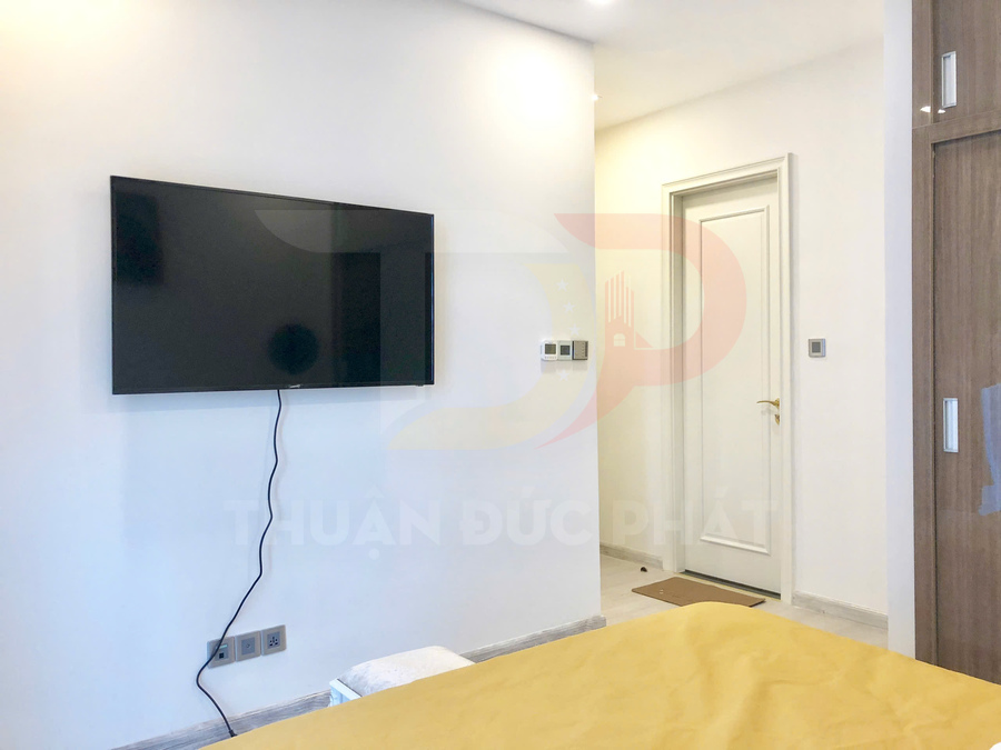 Tivi màn hình phẳng treo tường trong phòng ngủ hiện đại tông trắng và gỗ