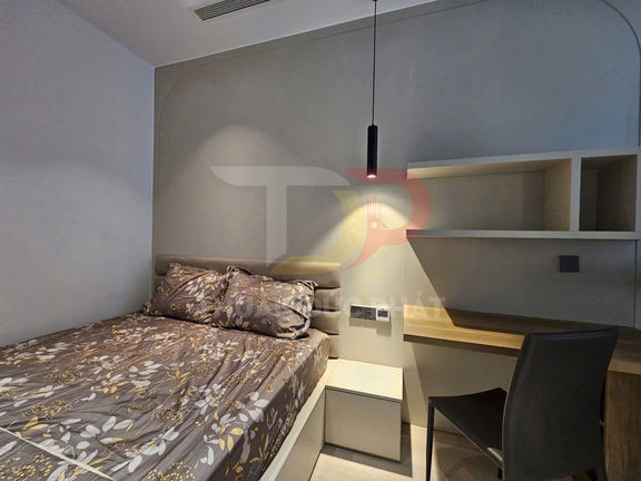 Phòng ngủ nhỏ hiện đại với giường đôi ga hoa, bàn làm việc gỗ và kệ treo tường cạnh đèn thả trần