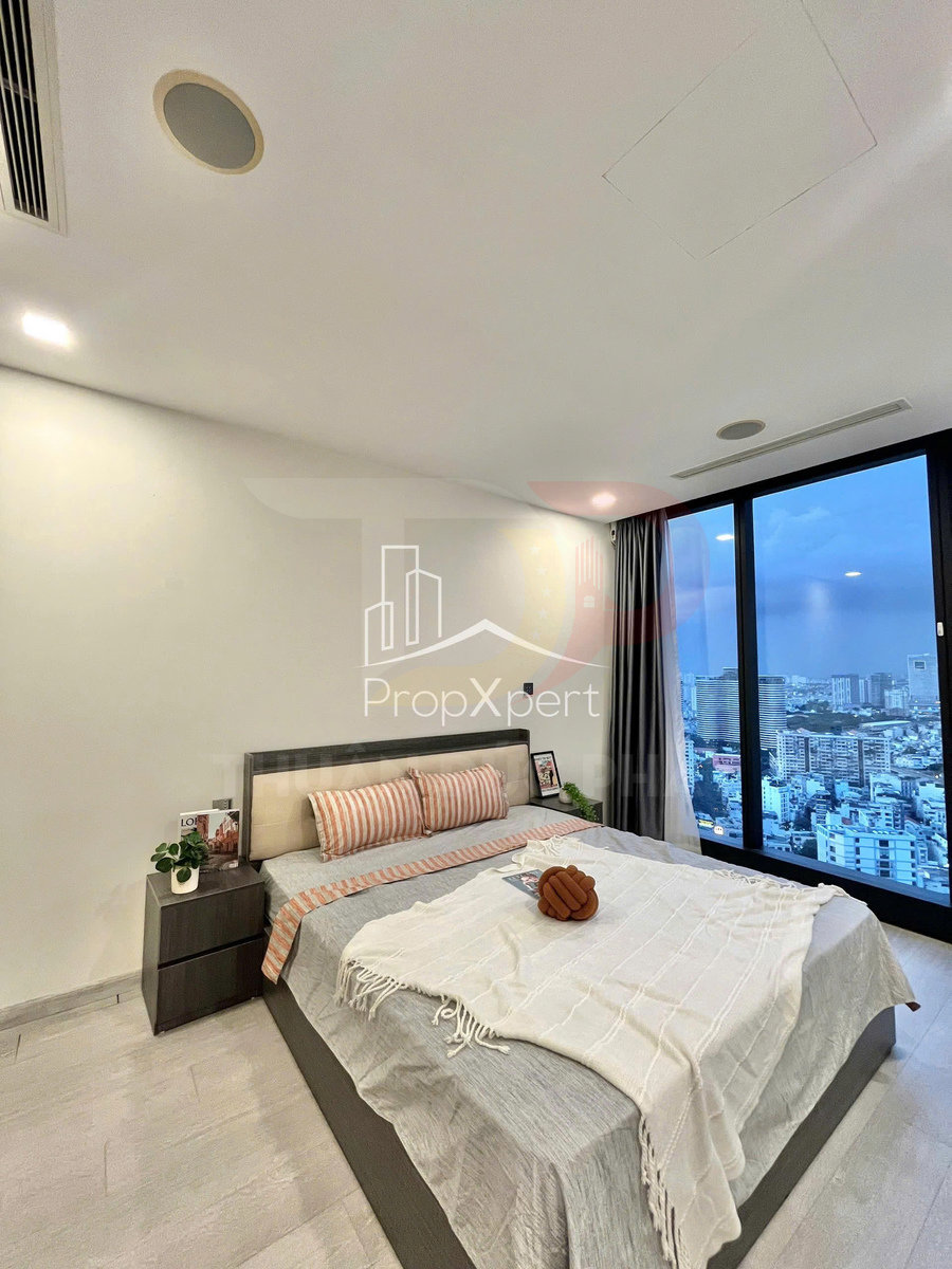 Phòng ngủ chung cư hiện đại với giường đôi, ga xám, chăn trắng và cửa kính lớn nhìn ra thành phố