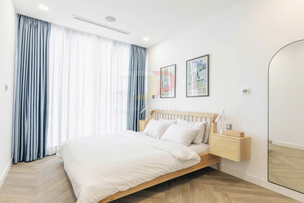 Phòng ngủ hiện đại với giường gỗ, chăn ga gối trắng, rèm cửa xanh và gương đứng lớn cạnh tường