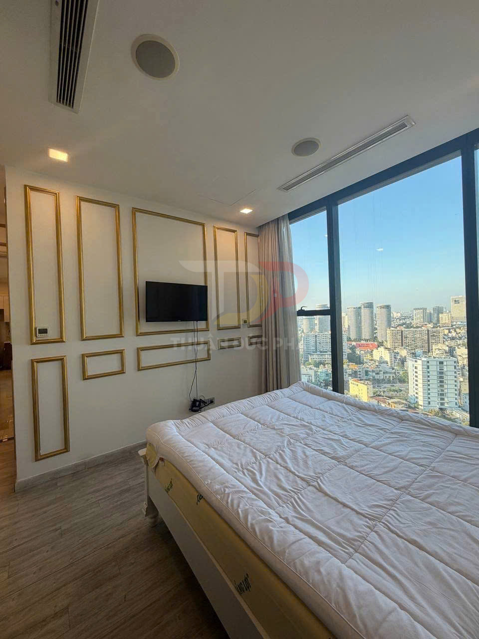 Phòng ngủ chung cư hiện đại với giường nệm trắng cạnh cửa sổ kính lớn nhìn ra thành phố