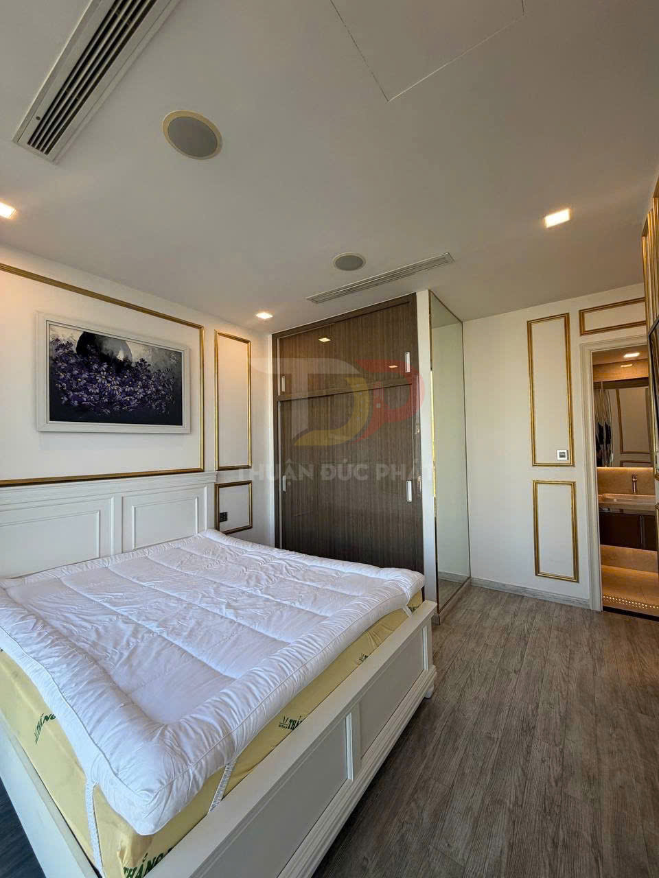Phòng ngủ hiện đại với giường nệm trắng, tủ quần áo gỗ cửa kính và sàn gỗ sáng màu
