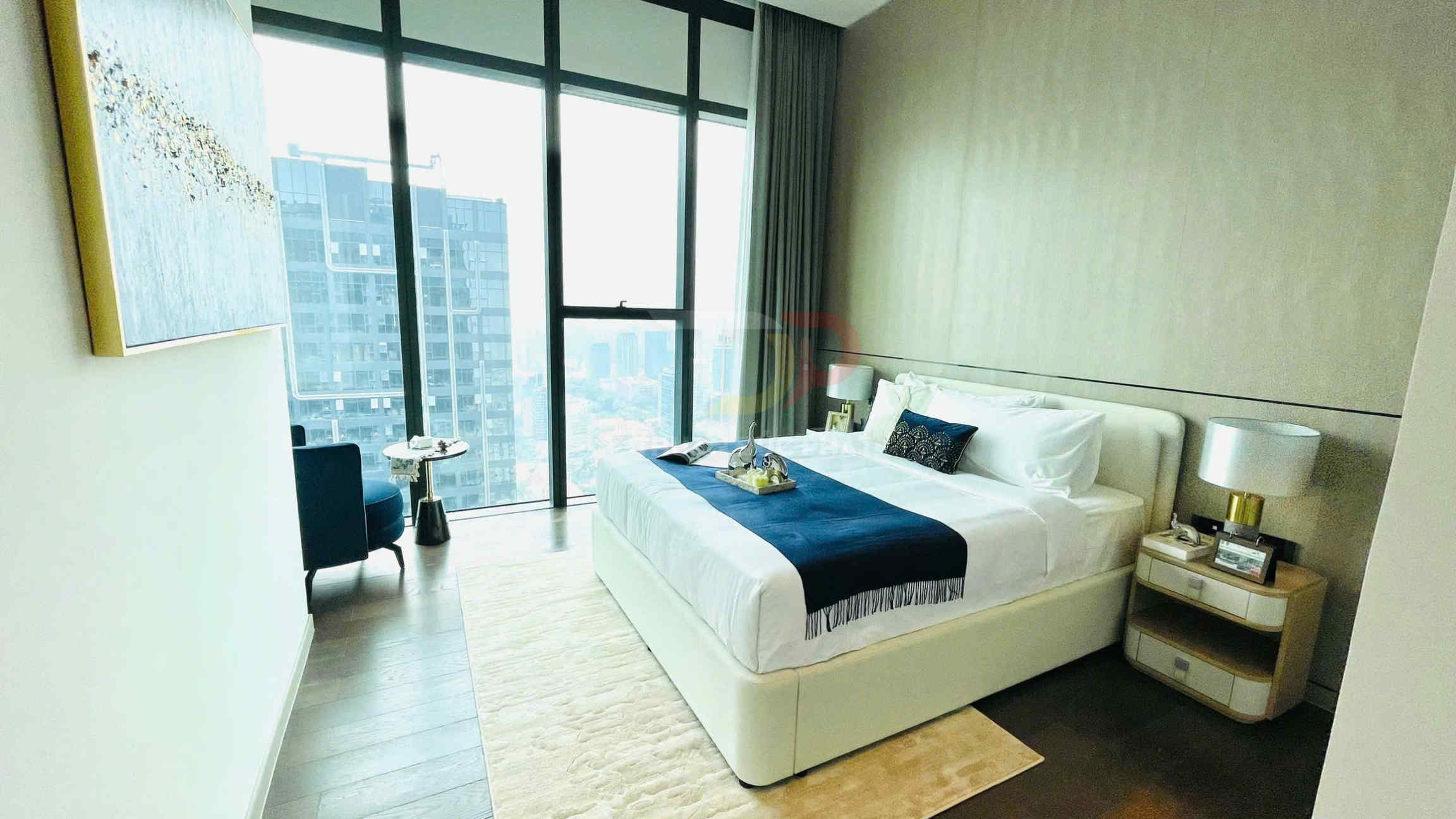 Phòng ngủ căn hộ cao cấp với giường đôi trắng, ga xanh đậm và cửa kính lớn nhìn ra thành phố
