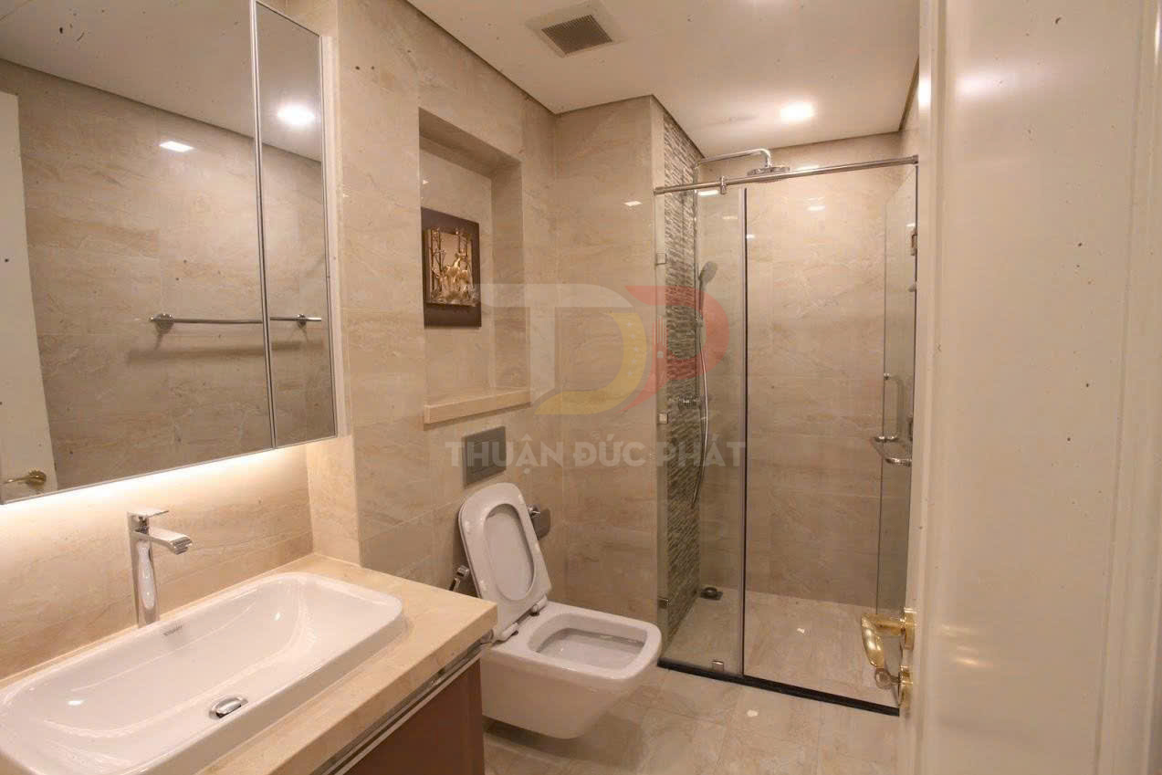 Phòng tắm hiện đại với bồn rửa, bồn cầu và buồng tắm kính vách đá sáng màu