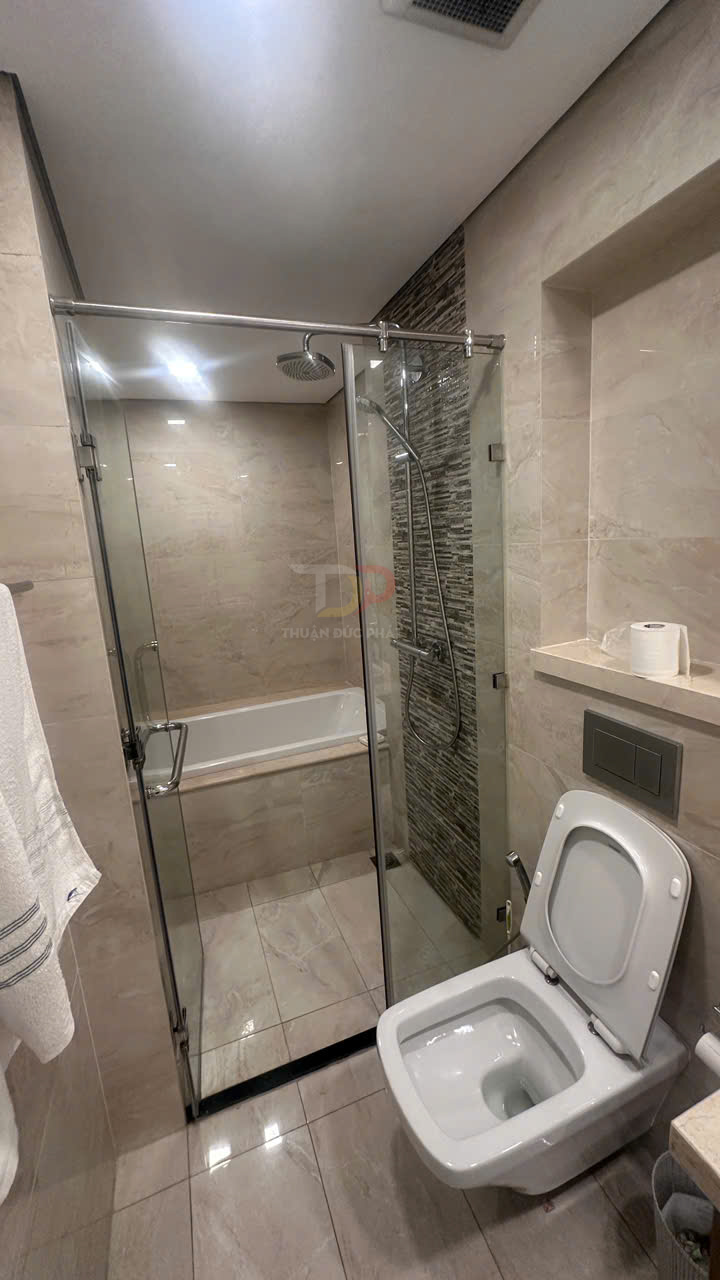 Phòng tắm hiện đại với bồn cầu, buồng tắm kính kèm vòi sen và bồn tắm nằm ốp gạch sáng màu