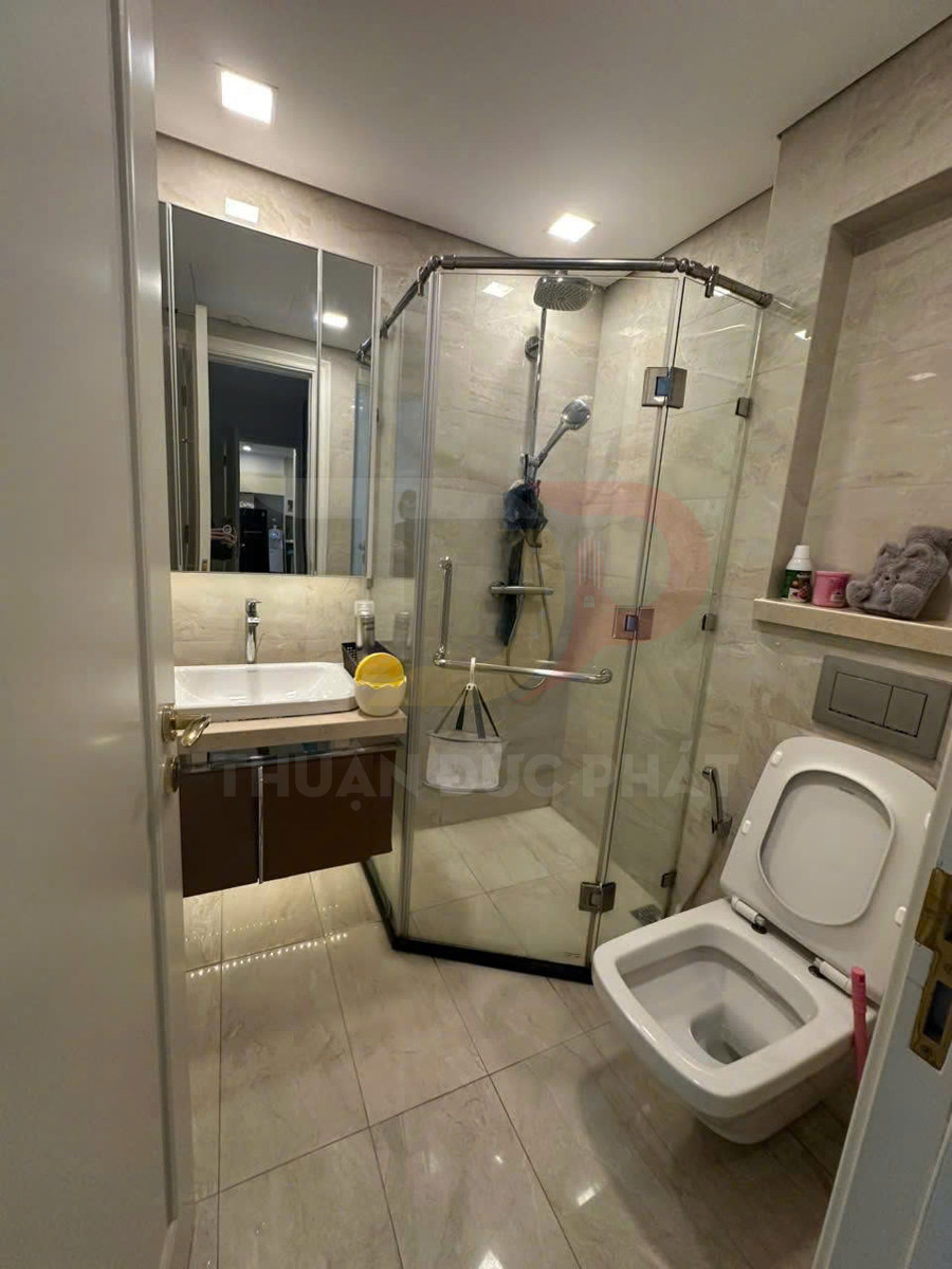 Phòng tắm hiện đại với bồn cầu, buồng tắm kính đứng, lavabo và gương lớn sáng đèn