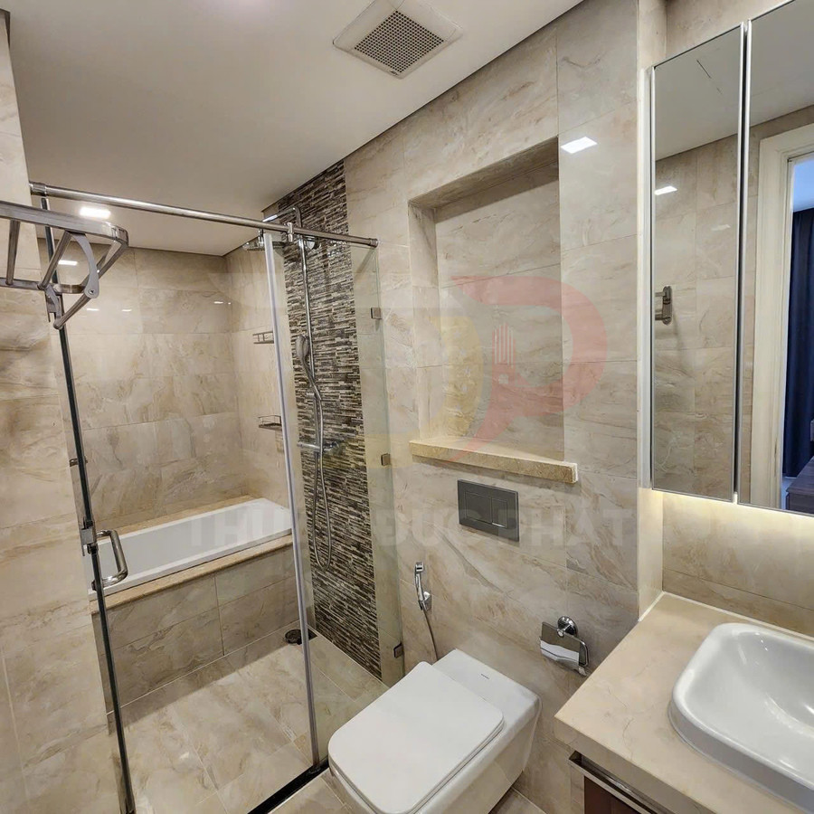 Phòng tắm hiện đại với bồn tắm kính, vòi sen đứng, bồn cầu treo tường và lavabo đá marble sáng