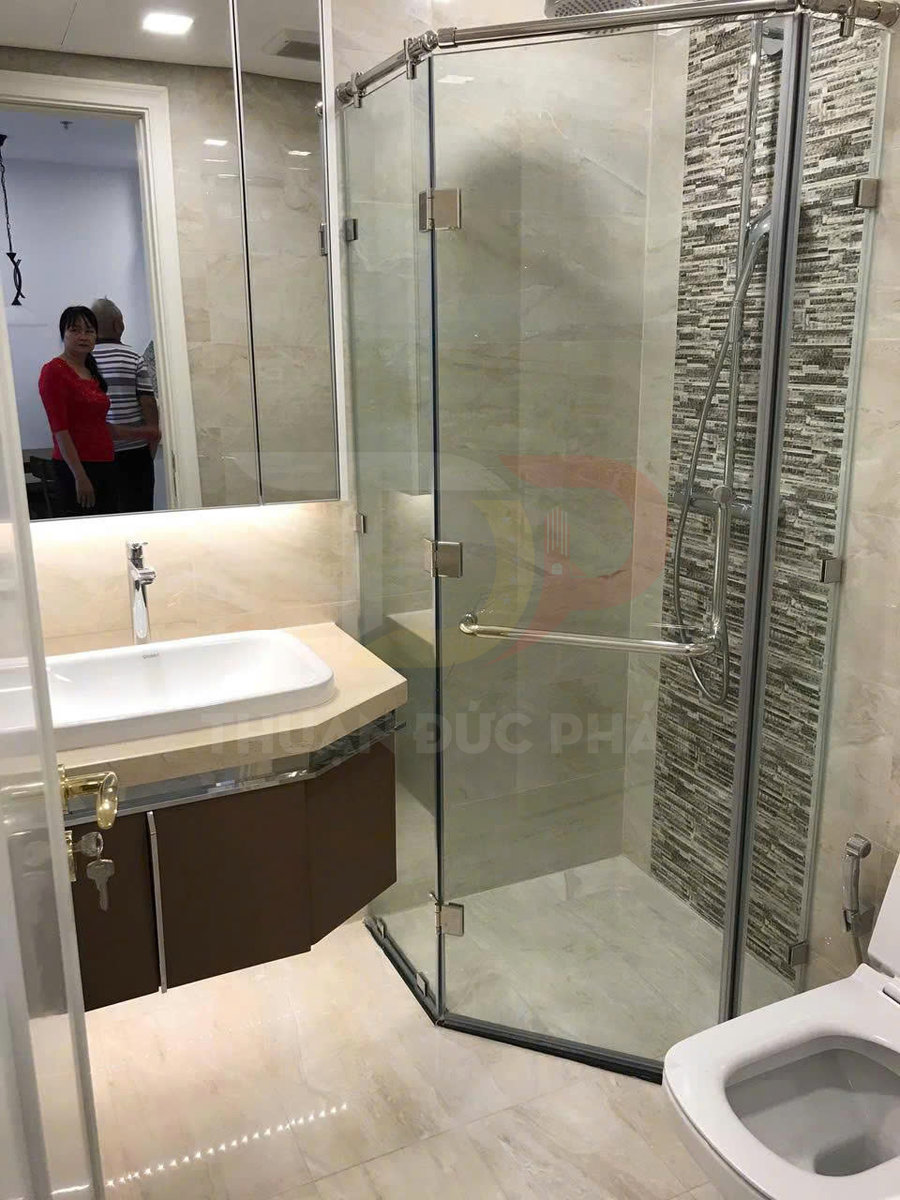 Phòng tắm hiện đại với vách kính tắm đứng, lavabo mặt đá và bồn cầu sứ trắng