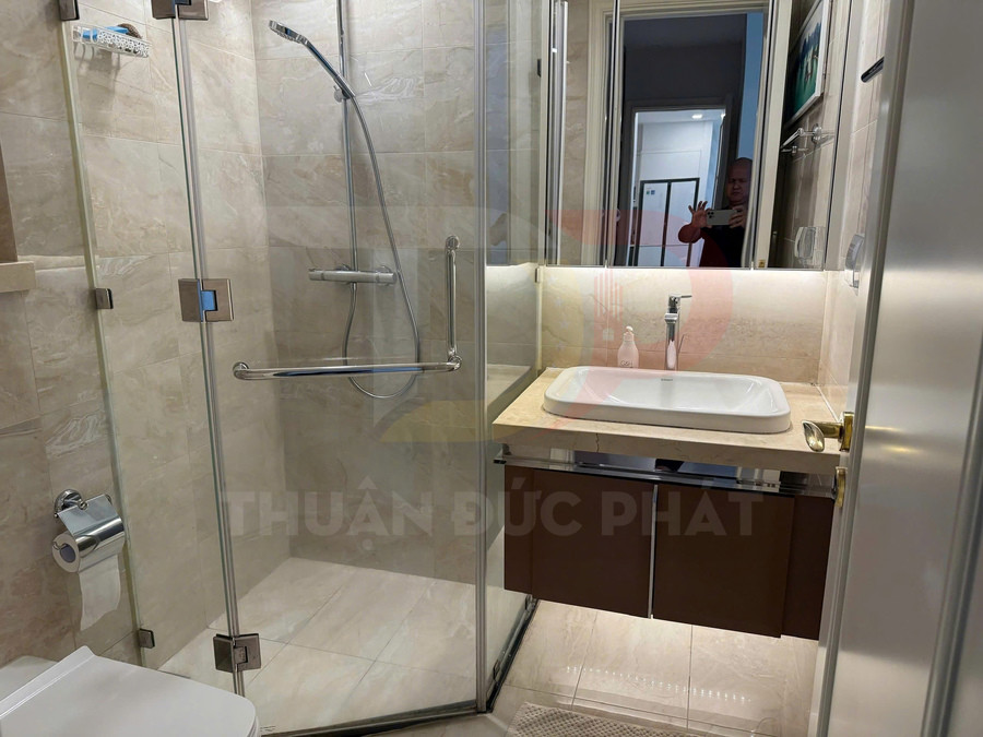 Phòng tắm hiện đại với buồng tắm kính, vòi sen inox và lavabo đặt trên mặt đá sáng