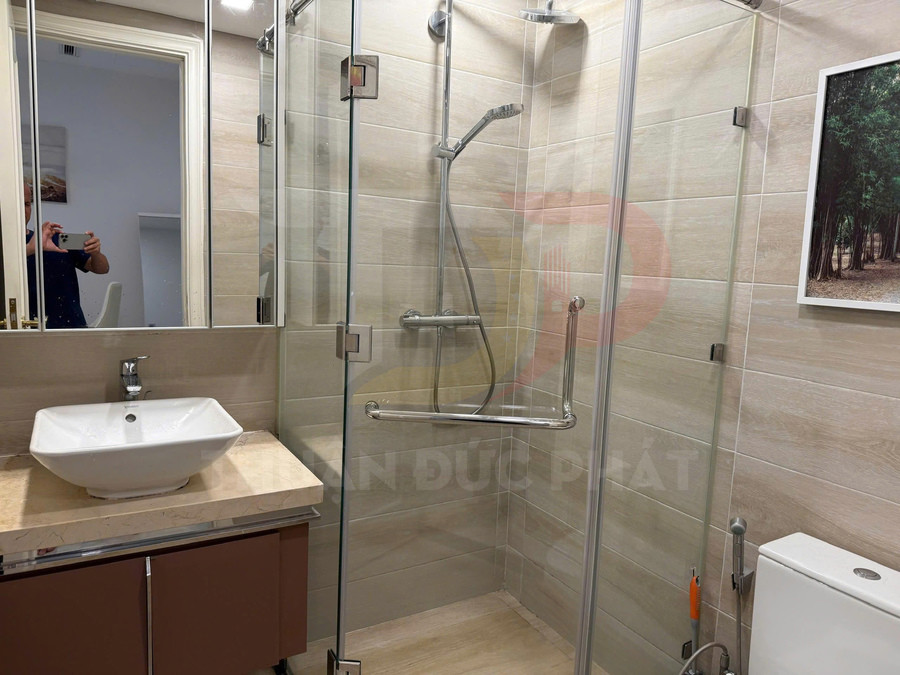 Phòng tắm hiện đại với buồng tắm kính, vòi sen inox, lavabo đặt bàn và bồn cầu trắng