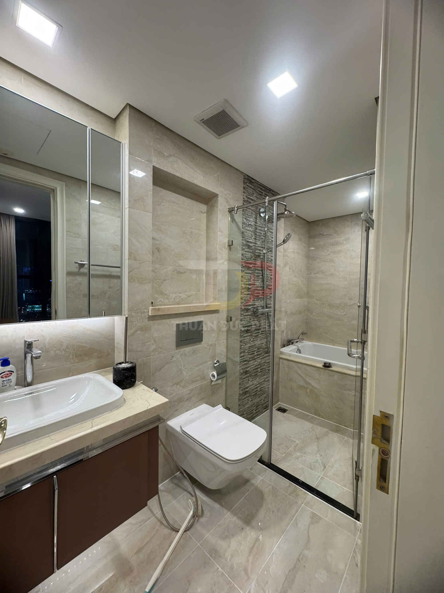 Phòng tắm hiện đại với bồn rửa, bồn cầu treo tường và khu tắm kính kèm bồn tắm nằm