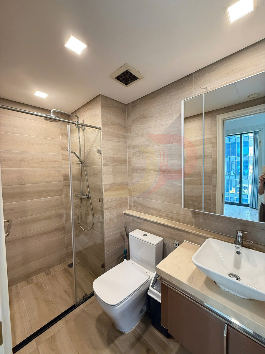 Phòng tắm hiện đại với buồng tắm kính, bồn cầu sứ trắng và lavabo vuông trên mặt đá