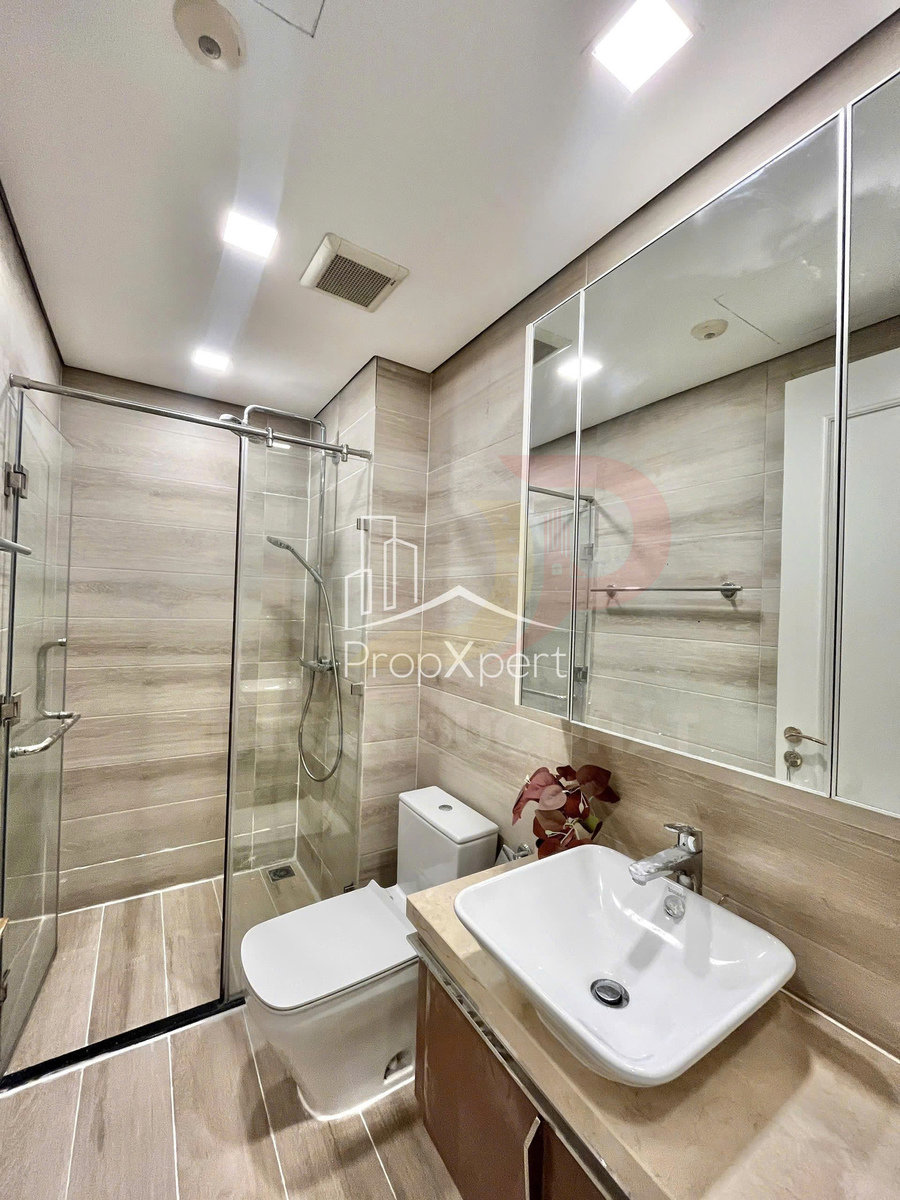 Phòng tắm hiện đại với buồng tắm kính, bồn cầu và lavabo đặt trên mặt đá sáng màu