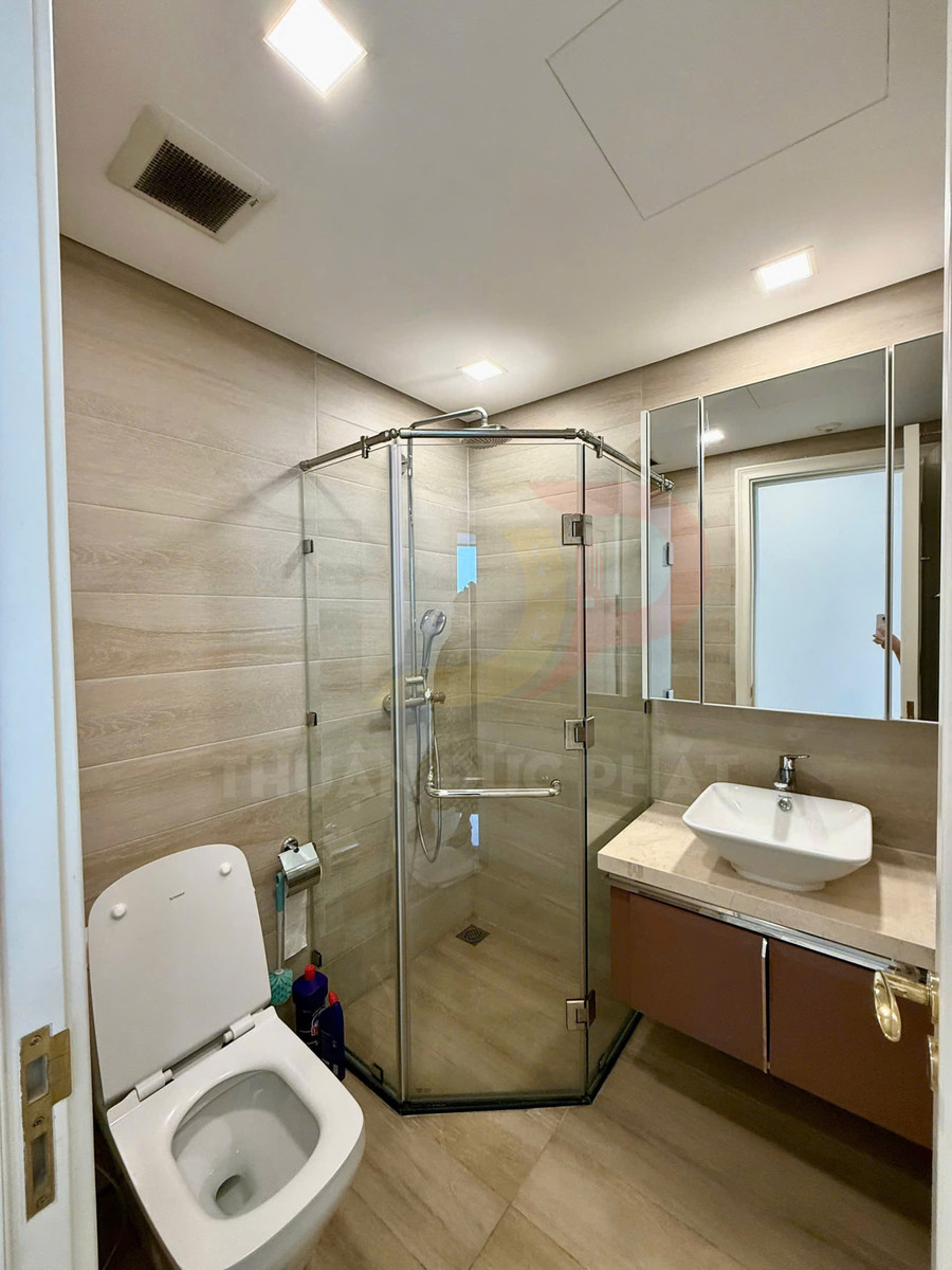 Phòng tắm hiện đại với buồng tắm kính đứng, bồn cầu và lavabo đặt trên tủ gỗ gắn tường