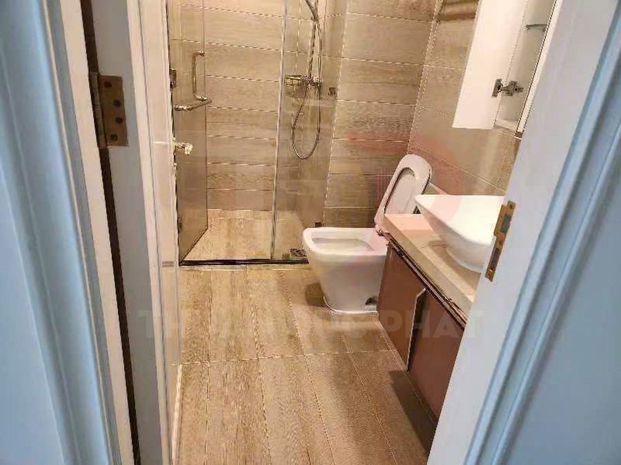 Phòng tắm hiện đại với bồn cầu, buồng tắm kính và lavabo đặt trên tủ gỗ