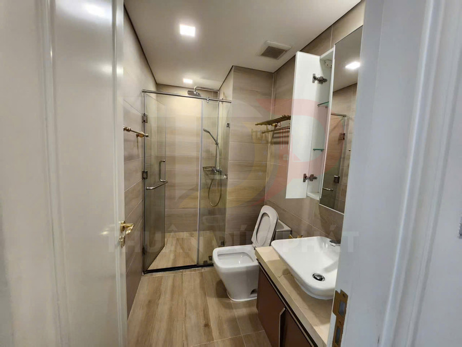 Phòng tắm hiện đại với buồng tắm kính, bồn cầu sứ trắng và lavabo đặt trên tủ gỗ