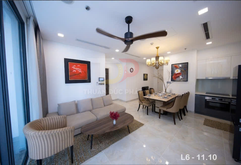 Phòng khách và bếp căn hộ hiện đại với sofa, bàn ăn gỗ, đèn trần và tủ bếp âm tường