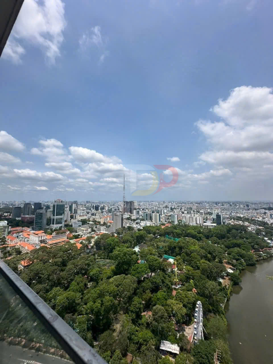 Toàn cảnh thành phố với công viên cây xanh, hồ nước và vòng quay khổng lồ dưới bầu trời nhiều mây