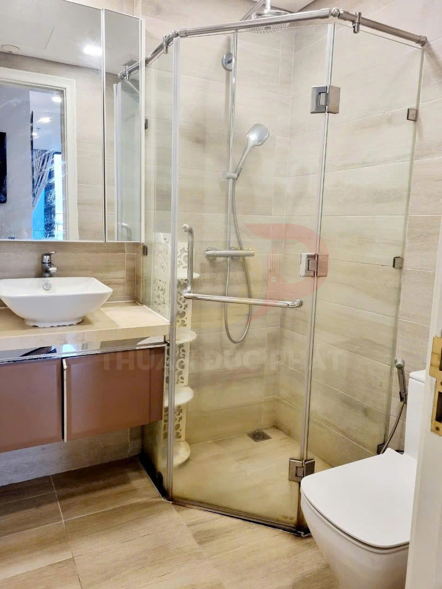 Phòng tắm hiện đại với vách kính tắm đứng, vòi sen, bồn rửa mặt và bồn cầu sứ trắng