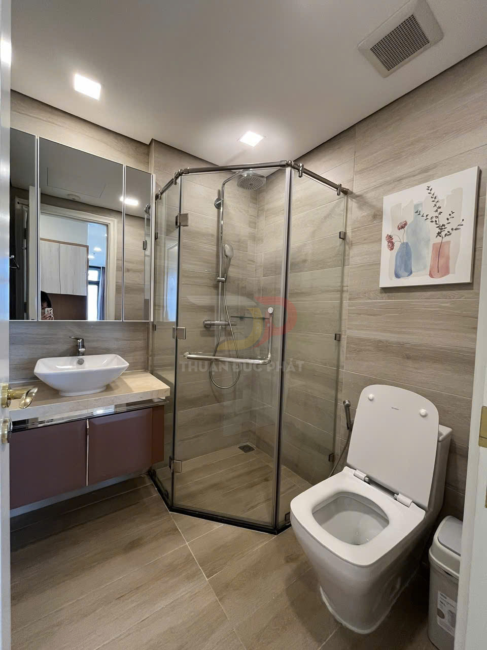 Phòng tắm hiện đại với buồng tắm kính, bồn cầu và lavabo đặt trên tủ gỗ sang trọng
