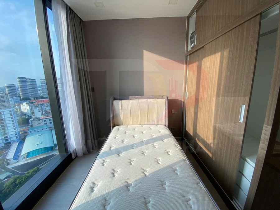 Giường đơn với nệm trắng cạnh cửa sổ kính lớn và tủ quần áo gỗ trong phòng ngủ sáng