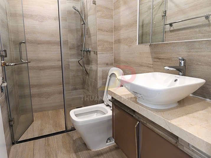 Bồn cầu và lavabo sứ trắng hiện đại trong phòng tắm kính vách gỗ sáng