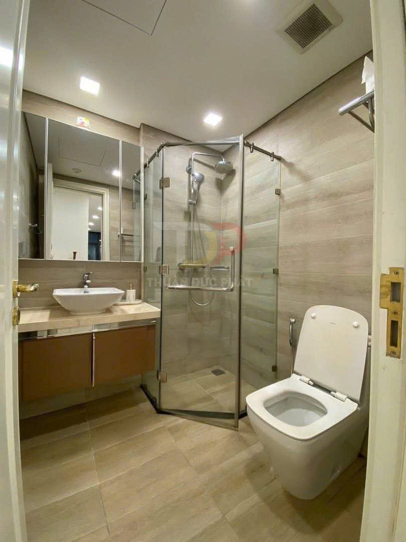 Phòng tắm hiện đại với bồn cầu, buồng tắm kính đứng và lavabo đặt trên tủ gỗ