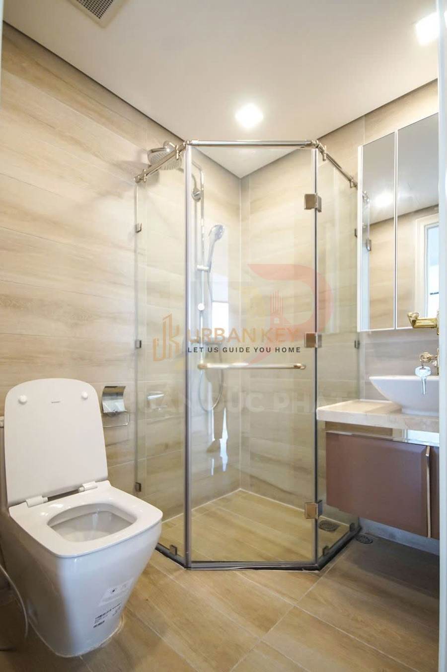 Phòng tắm hiện đại với buồng tắm kính đứng, bồn cầu và lavabo gắn tủ gỗ tông màu sáng