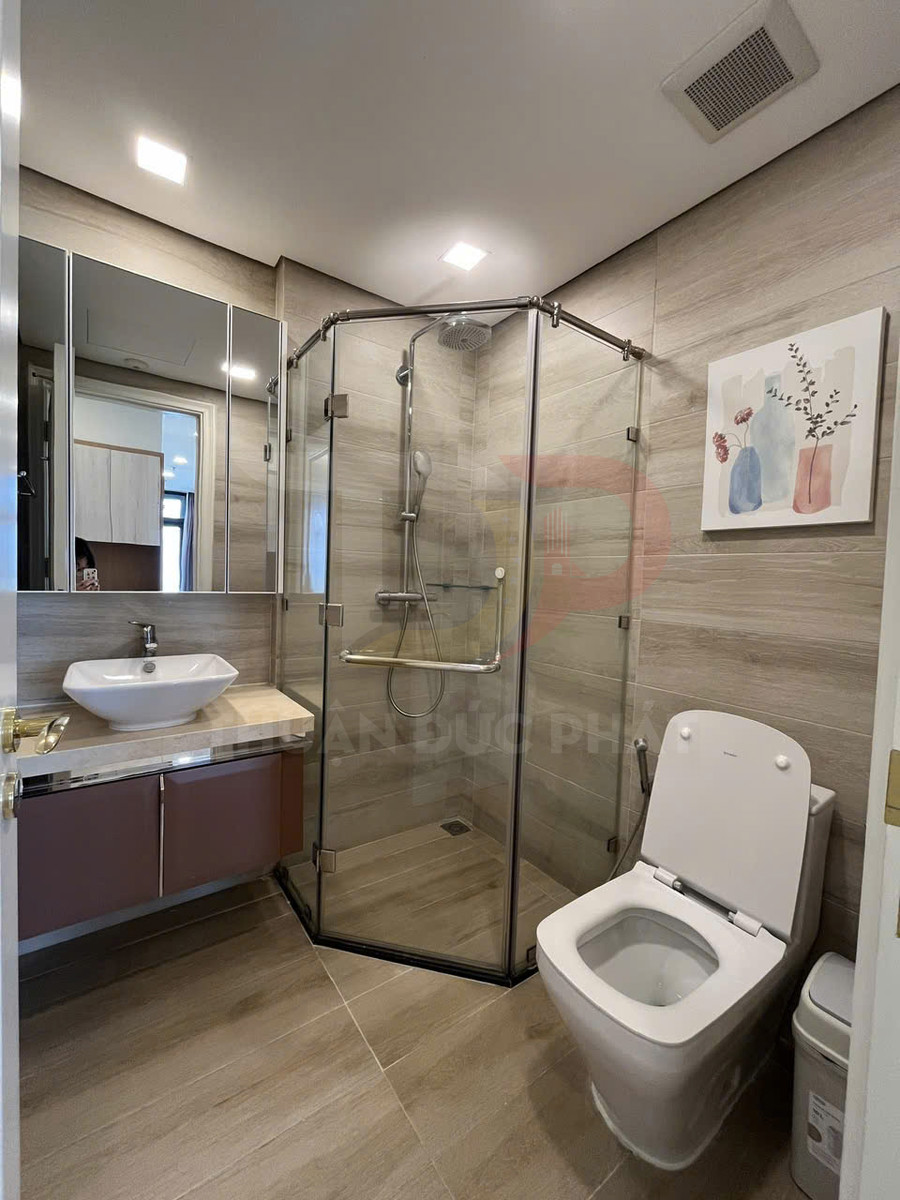 Phòng tắm hiện đại với buồng tắm kính, bồn cầu, lavabo đặt trên tủ gỗ và gương lớn