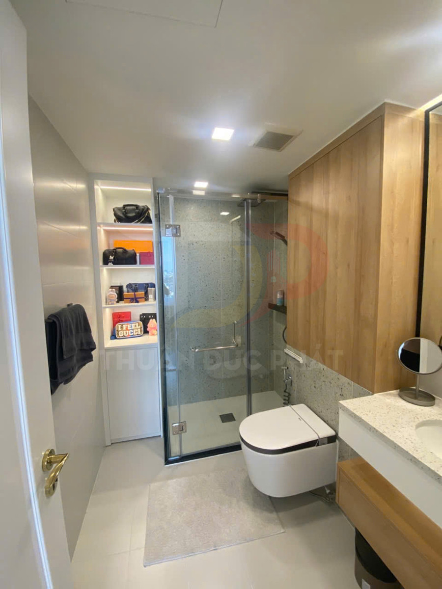 Phòng tắm hiện đại với bồn cầu treo tường, buồng tắm kính và tủ gỗ tiện nghi