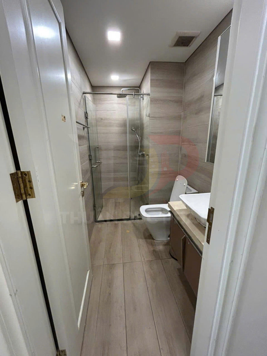Phòng tắm hiện đại với buồng tắm kính, bồn cầu và lavabo trên tủ gỗ tông màu sáng