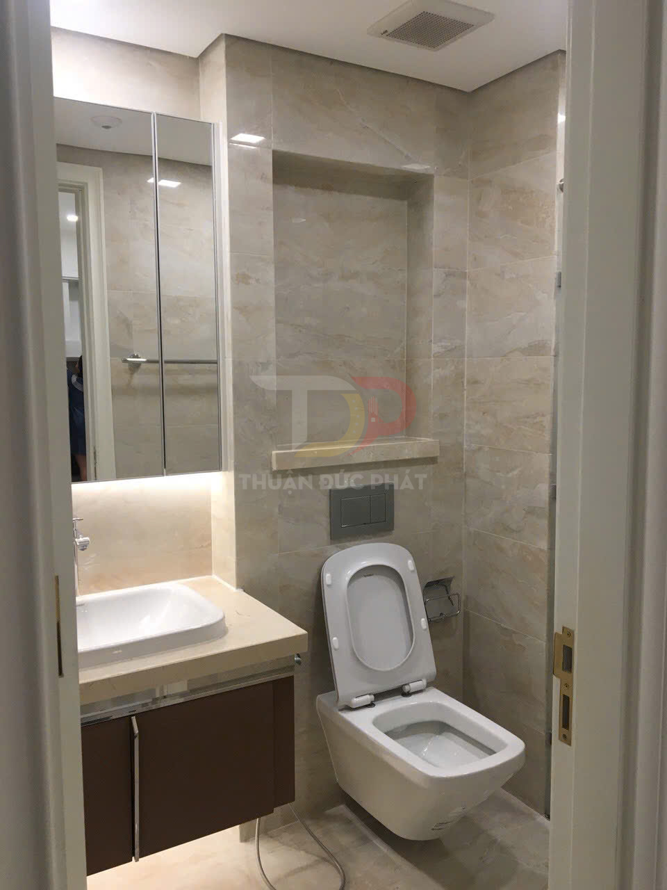Bồn cầu treo tường và lavabo hiện đại trong phòng tắm ốp đá màu kem