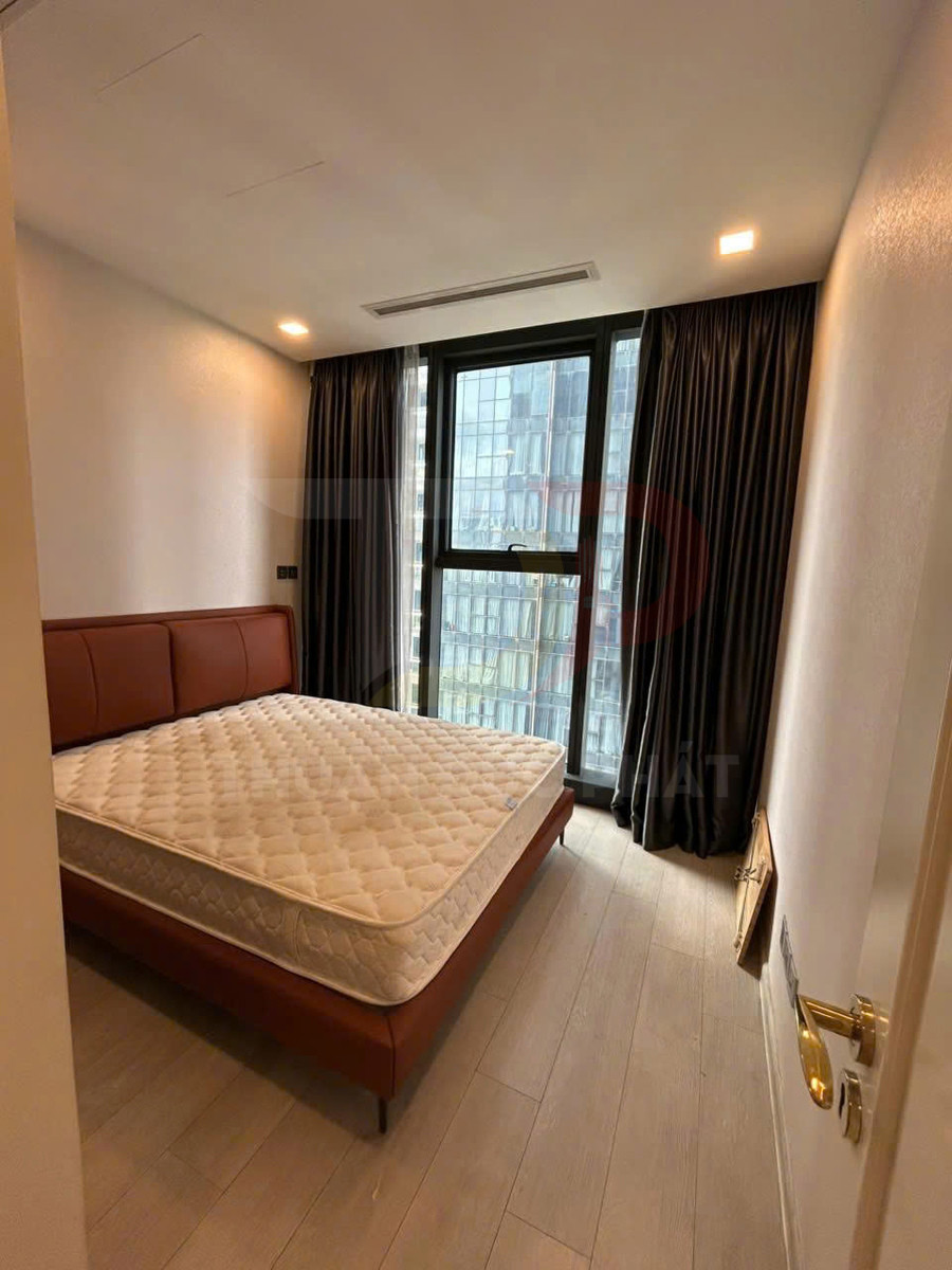 Phòng ngủ với giường da nâu và nệm trắng cạnh cửa sổ kính lớn có rèm tối màu
