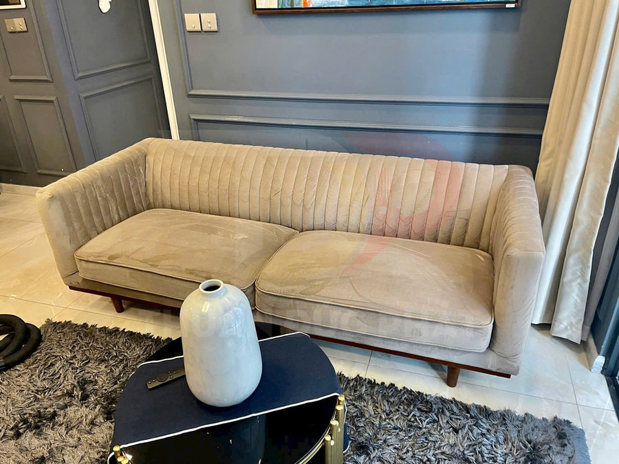 Sofa vải nhung màu be kiểu hiện đại trong phòng khách, phía trước là bàn trà nhỏ và bình gốm trắng