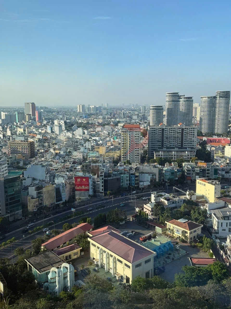 Toàn cảnh thành phố với nhiều tòa nhà cao tầng, đường lớn uốn cong và bầu trời trong xanh