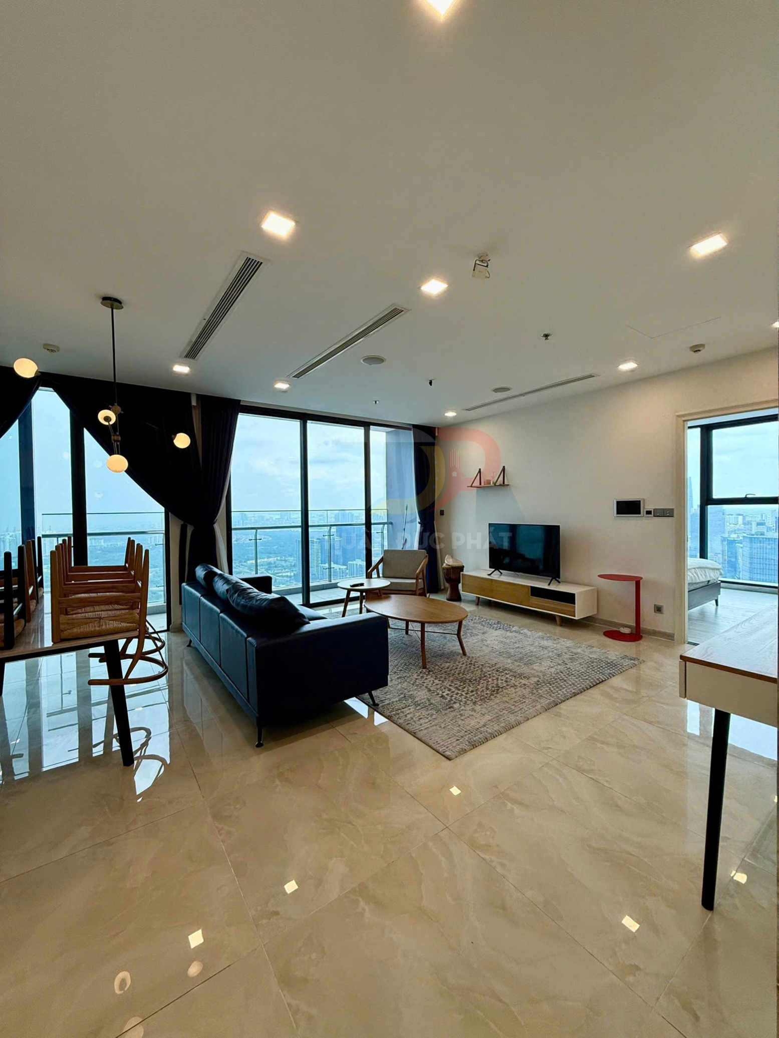 Phòng khách chung cư hiện đại với sofa da, bàn gỗ, tivi và cửa kính lớn nhìn ra thành phố