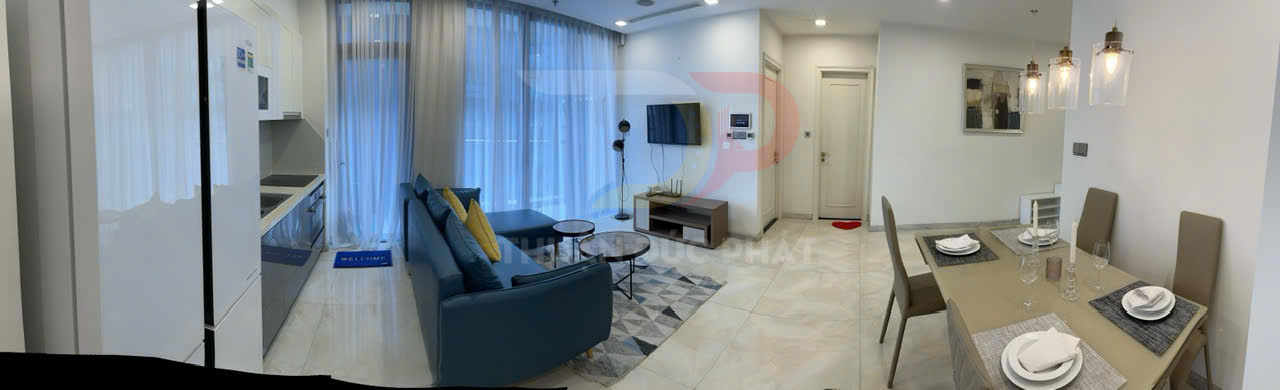 Căn hộ chung cư hiện đại với bếp, sofa xanh, bàn ăn bốn ghế và tivi treo tường trong không gian sáng rộng