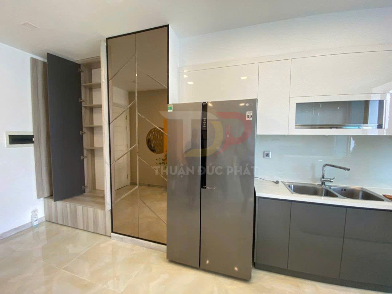Tủ lạnh LG hai cánh đặt cạnh tủ bếp hiện đại và tủ gương trong không gian bếp sáng sạch