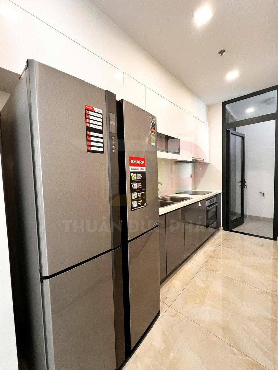 Tủ lạnh Sharp màu bạc đặt trong bếp hiện đại cạnh tủ bếp và bồn rửa inox